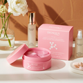 Open jar of pink hydrogel eye patches with its applicator spatula, beside the box